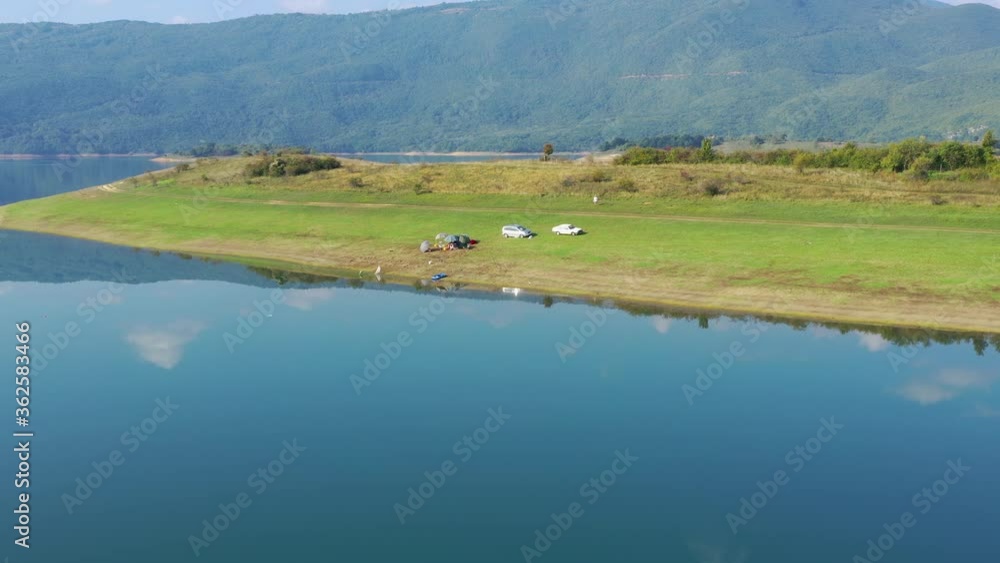 Cars parked on Rama Lake in Bosnia and Herzegovina shore near a small campsite, Aerial dolly in shot Cars parked on Rama Lake in Bosnia and Herzegovina shore near a small campsite, Aerial dolly in shot