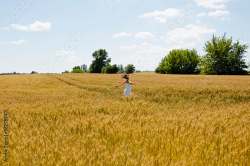 Beautiful girl model in white dress run on field, sunlight. hippie girl on wheat field. Portrait of a romantic woman running across the field. carefree girl with windy hair. among the rich harvest