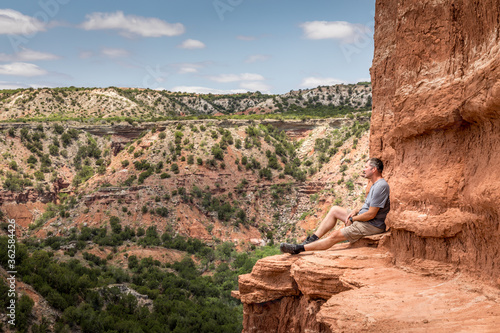 Man sitting on the edge of the Lighthouse Rock, Palo Duro Canyin State Park, Texas photo