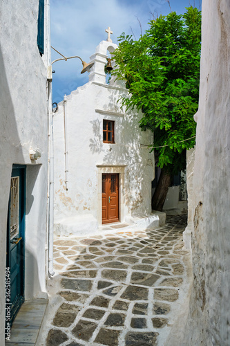 Fototapeta Naklejka Na Ścianę i Meble -  Picturesque scenic narrow Greek streets with traditional whitewashed houses with blue doors windows of Mykonos town and orthodox church in famous tourist attraction Mykonos island, Greece