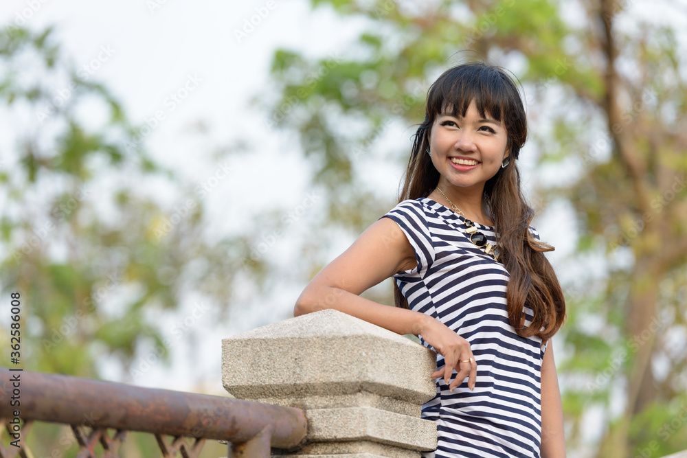 Happy young beautiful Asian woman thinking at the park Happy young beautiful Asian woman thinking at the park