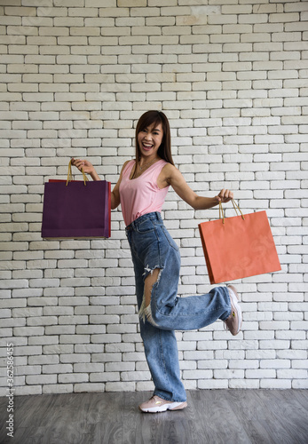 Asian attractive woman holding many colourful shopping bags with smiling face/lifestyle shopping
