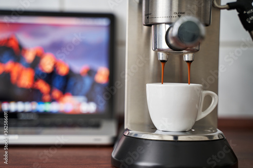 Espresso läuft von einer Siebträgermaschine in eine Espresso Tasse. Unscharfer Hintergrund. Leckerer italienischer Kaffee. photo