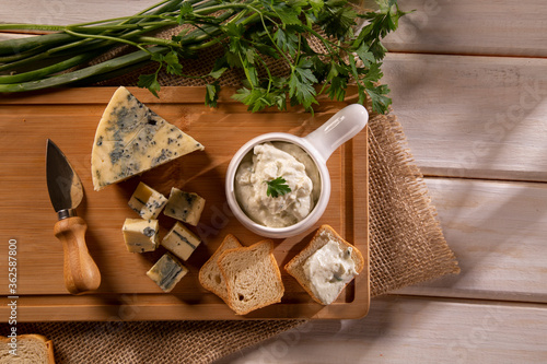Blue cheese cream and toasted bread on wood background. Pate de gorgonzola in Brazil.
