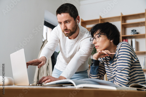 Photo of young colleges discussing project while working in office