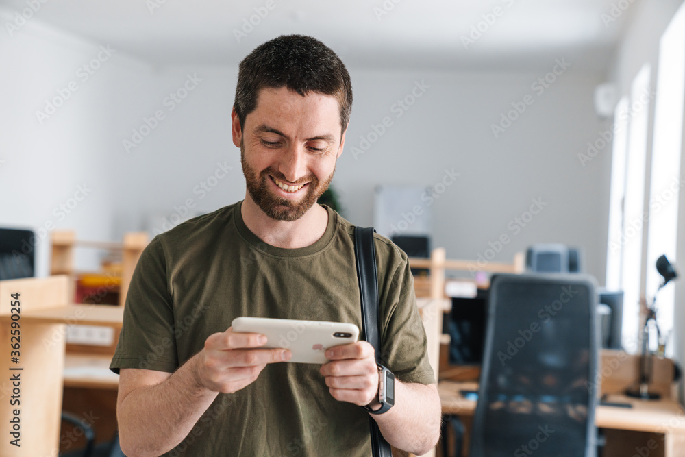 Photo of cheerful man smiling and playing online game on cellphone