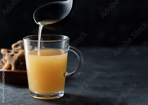 Homemade Beef Bone Broth in Glass Storage Jar on a black background with copy space
