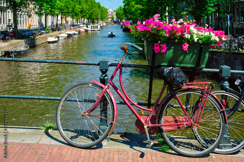 Typical Amsterdam view - Amsterdam canal with boats and parked bicycles on a bridge with flowers. Amsterdam, Netherlands