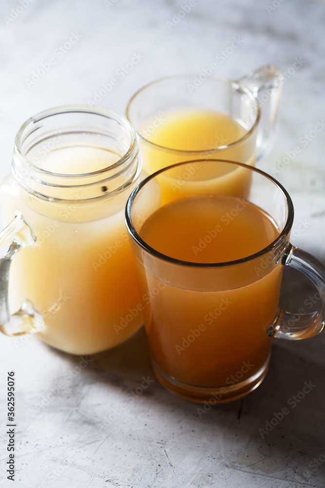 Homemade Beef Bone Broth in Glasses on a gray concrete background, close up Homemade Beef Bone Broth in Glasses on a gray concrete background, close up