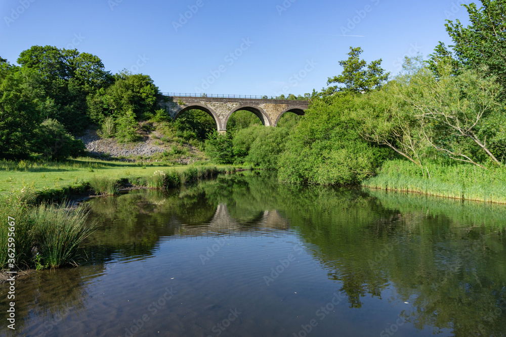 Vibrant, colourful image taken on a warm summer evening of the Monsal Head Bridge across the River Wye at Monsal Head in the Peak District in Derbyshire. 