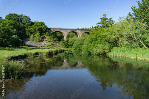 Vibrant, colourful image taken on a warm summer evening of the Monsal Head Bridge across the River Wye at Monsal Head in the Peak District in Derbyshire. 