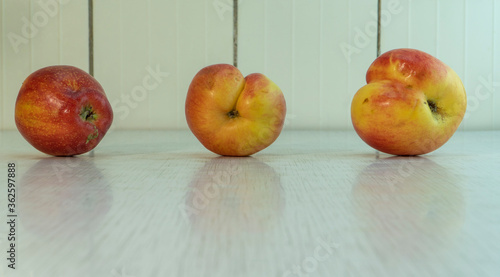 Three misshapen apples red and yellow colour reflect in rustic table. Homegrown fruits is best for diet because it contain many vitamins and microelements. Landscape picture with copy space.