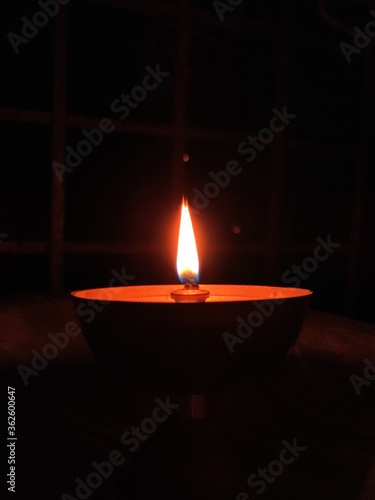 A gold color diya(lamp) with orange color light in a apartment balcony.