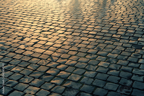 Cobblestone pavement stones at sunset light, old European street background.
