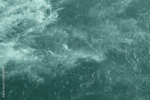 The raging waters of the river Ganges in Rishikesh. Top view of the raging elements. White foam on blue water.