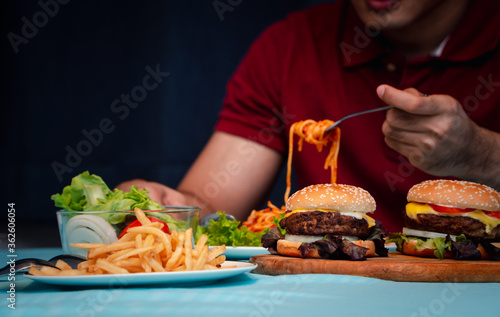 Man holding hamburger on the wooden plate after delivery man delivers foods at home. Concept of binge eating disorder (BED) and Relaxing with Eating junk food. photo