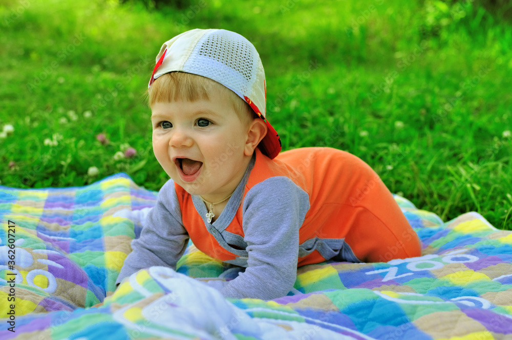 Happy smiling baby in the park on the bedspread. Happy smiling baby in the park on the bedspread.