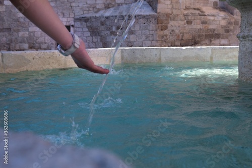 a young girl's hand cooling off in a stone fountain