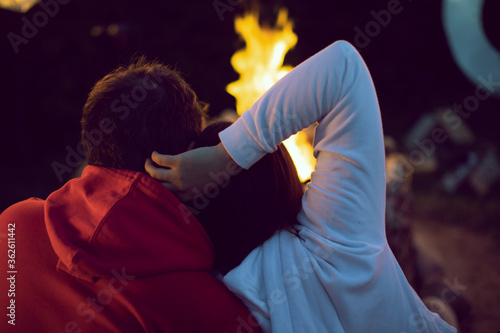 couple of lovers looking at fire enjoying campfire in nature at romantic party by bonfire back view. Great warm evening On Vacation Outdoors. concept of active recreation and travel