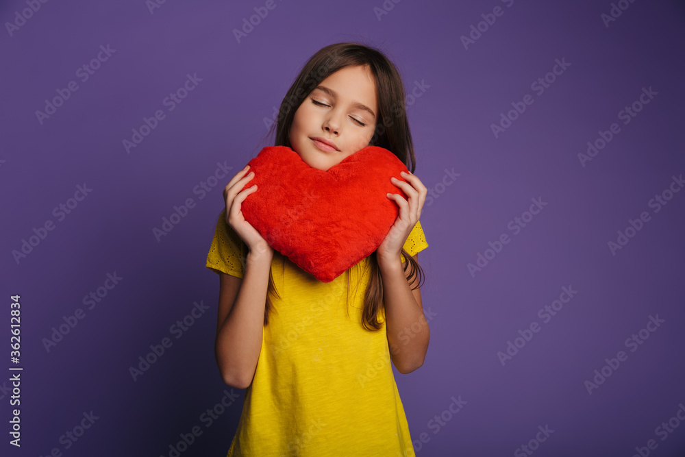 Photo of pleased girl holding soft toy heart with eyes closed Photo of pleased girl holding soft toy heart with eyes closed