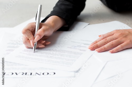 Woman's hand with pen signing document, close up