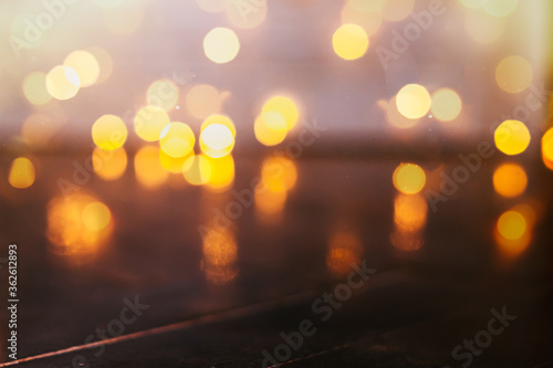 Empty rustic wooden table with blurred Christmas lights at background. Light gold bokeh of cafe restaurant in dark background.