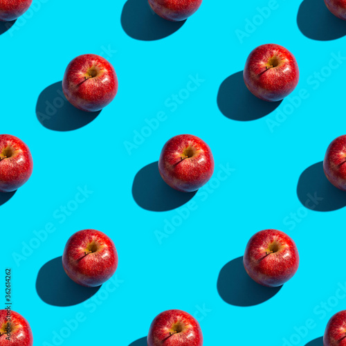 Seamless pattern of red apples on a bright blue background. Healthy organic food and diet concept.