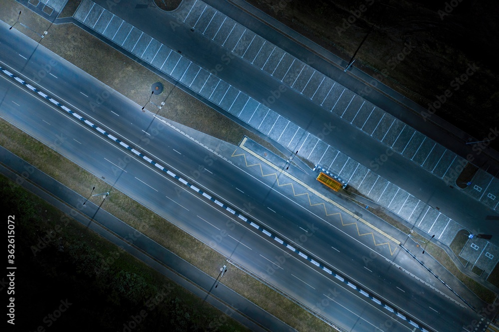Aerial view. New unfinished road with bus stop and parking lot at night. Aerial view. New unfinished road with bus stop and parking lot at night.
