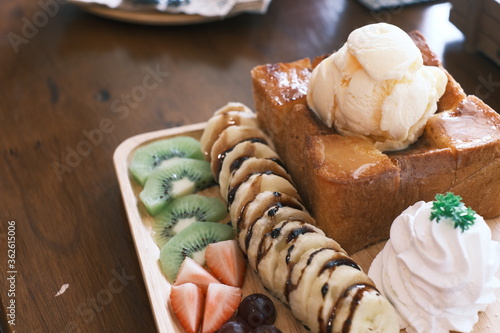 Delectable dessert with honey toast on top by ice cream and various fruits. close up, selective focus photo