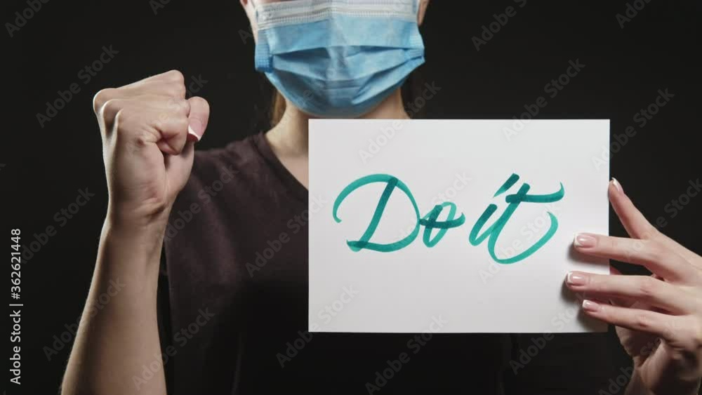 Do it. Fight coronavirus disease. Strong woman in face mask encouraging with fist gesture isolated on black. Do it. Fight coronavirus disease. Strong woman in face mask encouraging with fist gesture isolated on black.