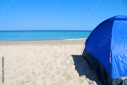 blue tourist tent on an empty sandy beach by the sea © Anna