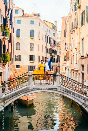 couple standing on the bridge crossing venice canals © phpetrunina14