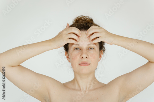 An attractive caucasian woman doing a morning exercises -yoga for the face, smoothing the muscles of the forehead with her fingers. The concept of self-care and rejuvenation.