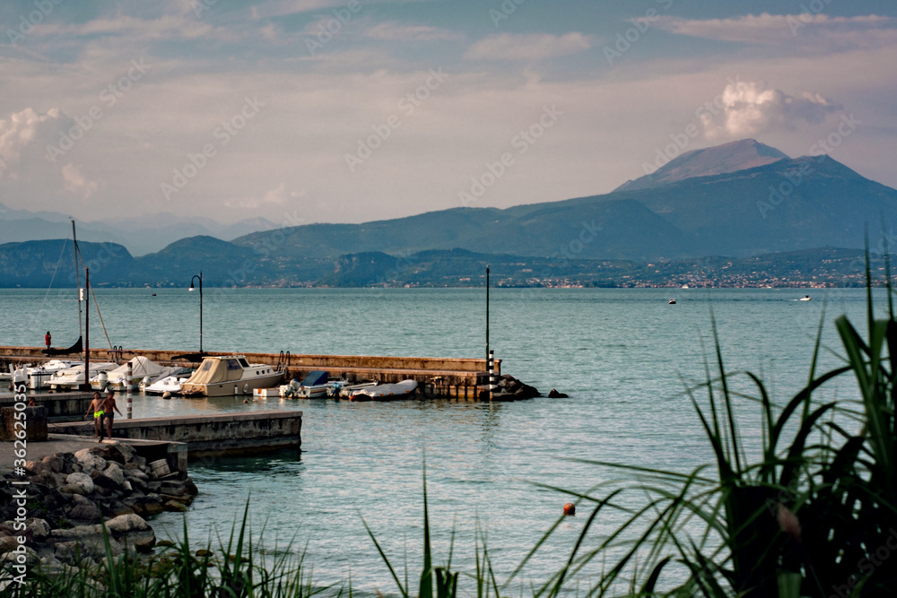Beautiful coastline on Lake Garda with a small harbor and mountains in the background