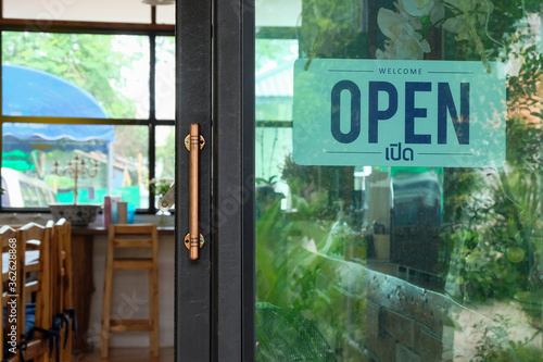 Text Open door sign and hanging up on glass door of coffee shop .