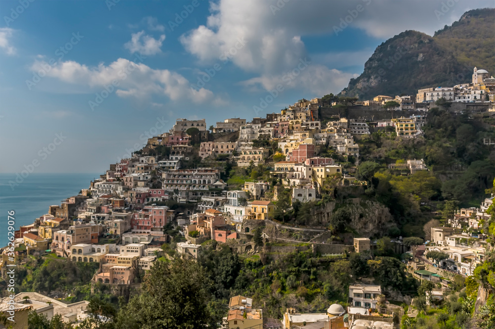 Pastel coloured buildings hug the hillside in Positano on the Amalfi coast, Italy beneath a cumulus sky