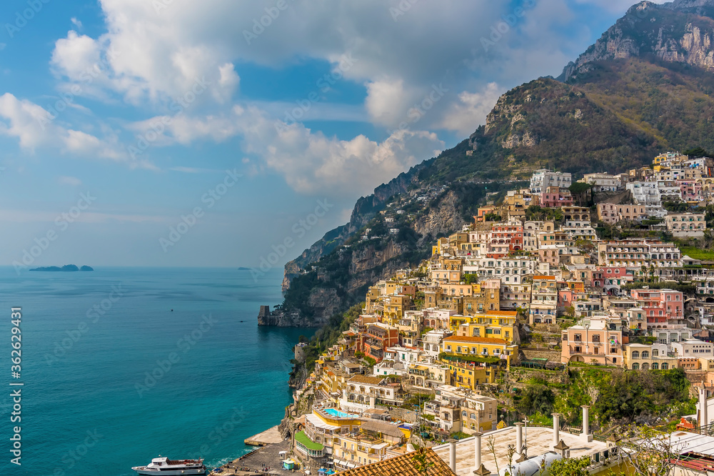 A view of the pastel coloured buildings of Positano on the Amalfi Coast, Italy with the islet of Gallo Lungo in the distance