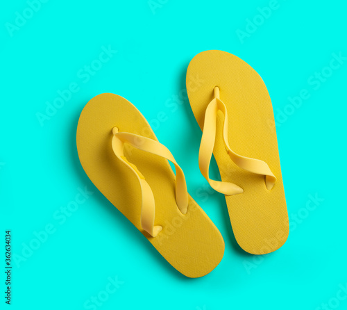 Yellow beach slippers on a turquoise background. summer concept