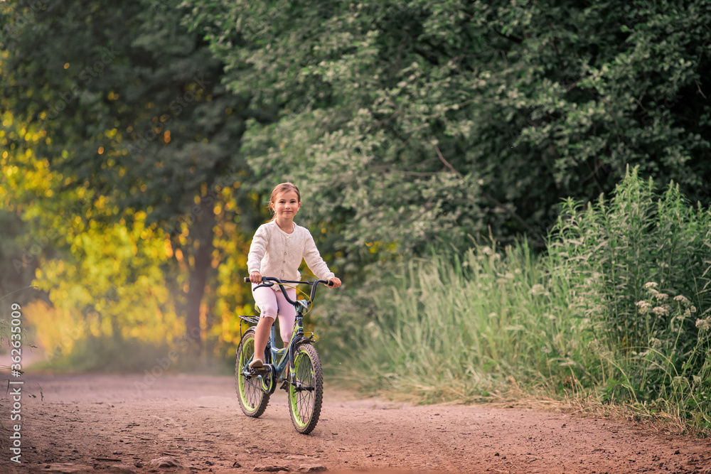 girl rides a bicycle in a summer park