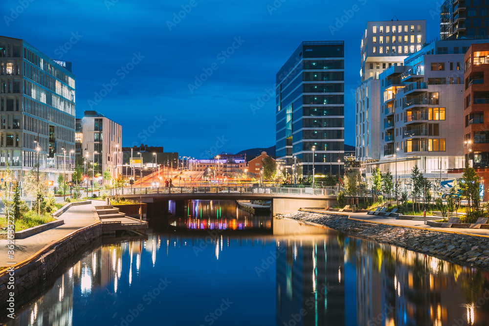 Fototapeta premium Oslo, Norway. Night View Embankment And Residential Multi-storey House In Gamle Oslo District. Summer Evening. Residential Area Reflected In Sea Waters