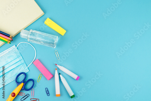 Useful for the return to school with mask and disinfectant gel on a blue background. Copy space.