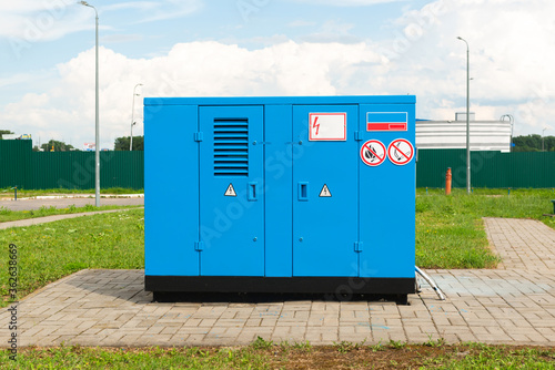 Outdoor emergency power generator with blue housing and special signs.