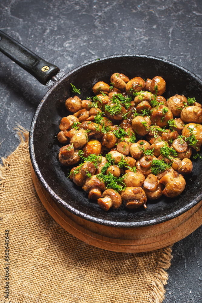 Delicious fried mushrooms in pan on stone table