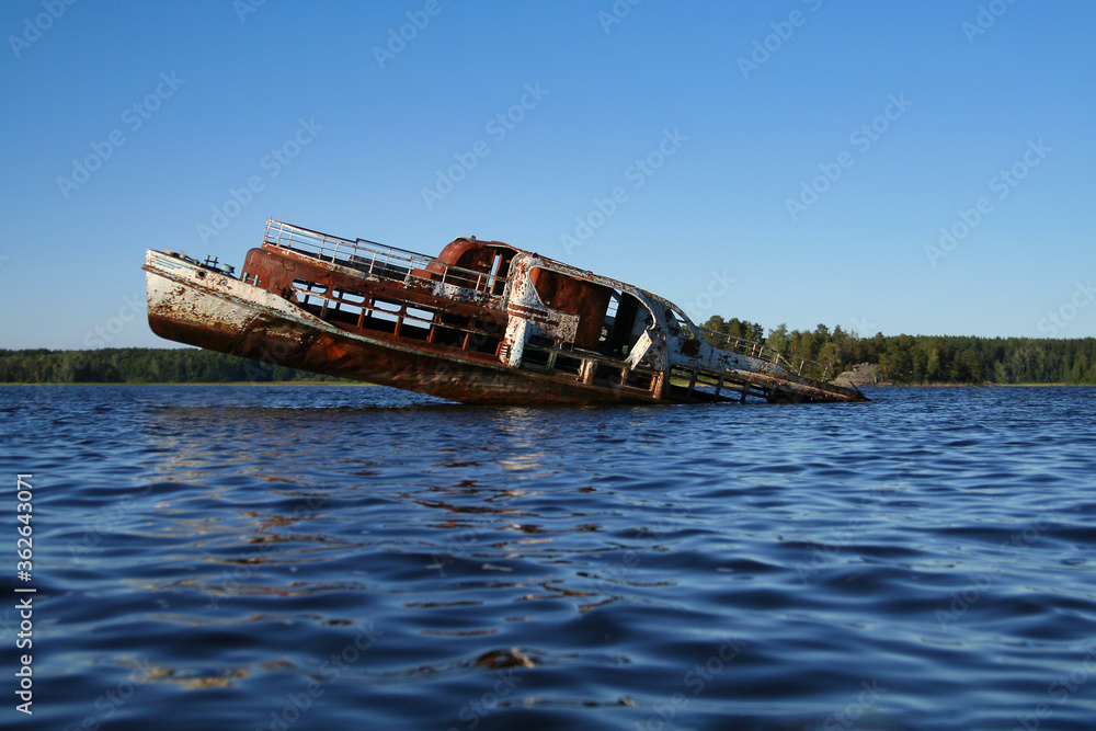 An old rusty wrecked ship is sinking in a lake. Passenger ship sinking in the water.
