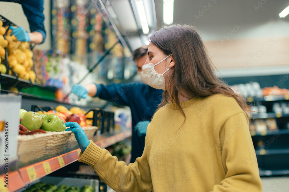 young woman in a protective mask buys apples