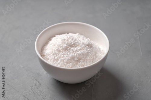 Coconut shavings in a white bowl on a concrete table
