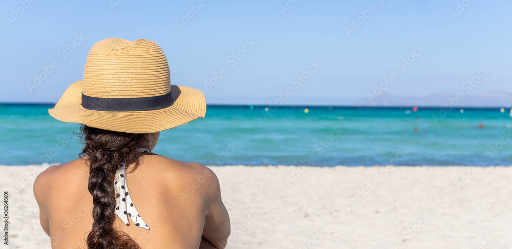 Pretty curly hair girl with straw hat on tropical beach.