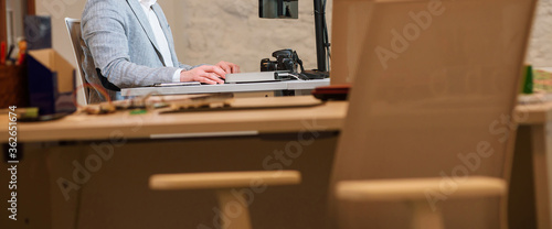 close-up photographer-designer working at a table holding a stylus of a graphic tablet in the river, in the foreground tables