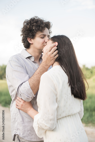 Young man gently kissing girlfriends head
