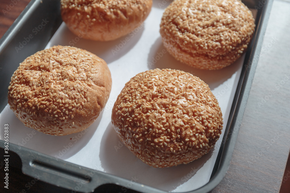 Hamburger bun with sesame seeds on the tray.